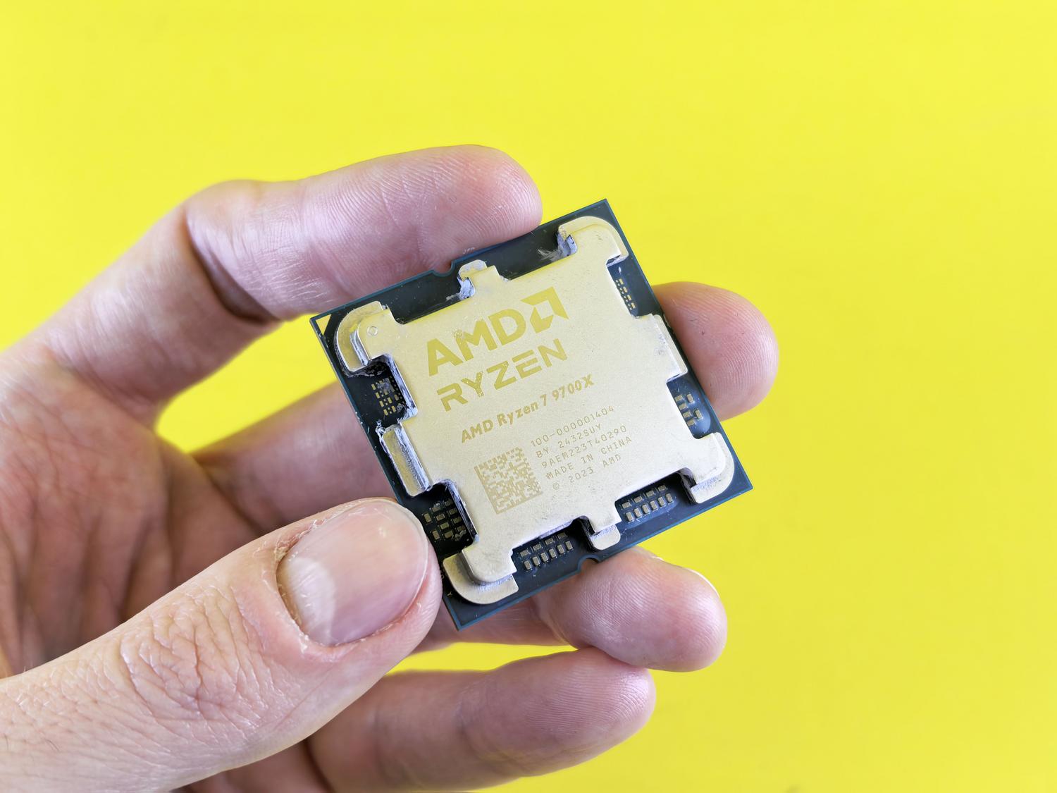 Procesador AMD Ryzen 7 9700X de última generación sostenido en una mano, representando la gama de alto rendimiento para gaming extremo.