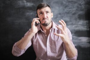 Hombre estresado hablando por teléfono móvil, representando la frustración de las llamadas spam.