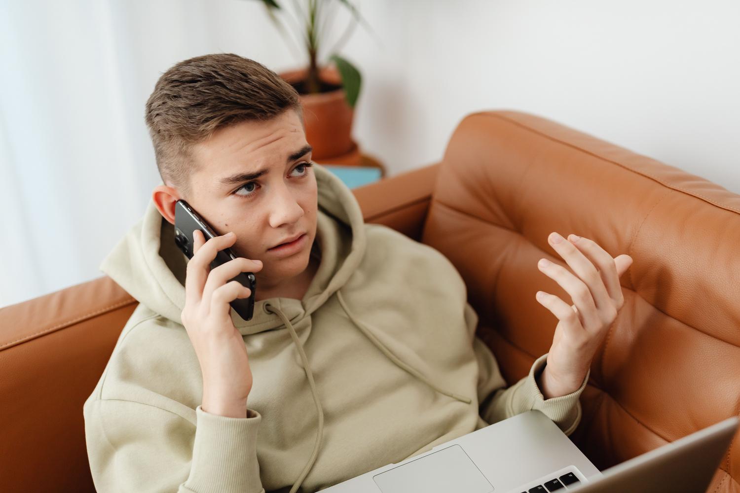Hombre joven preocupado al teléfono, reflejando la molestia del telemarketing.