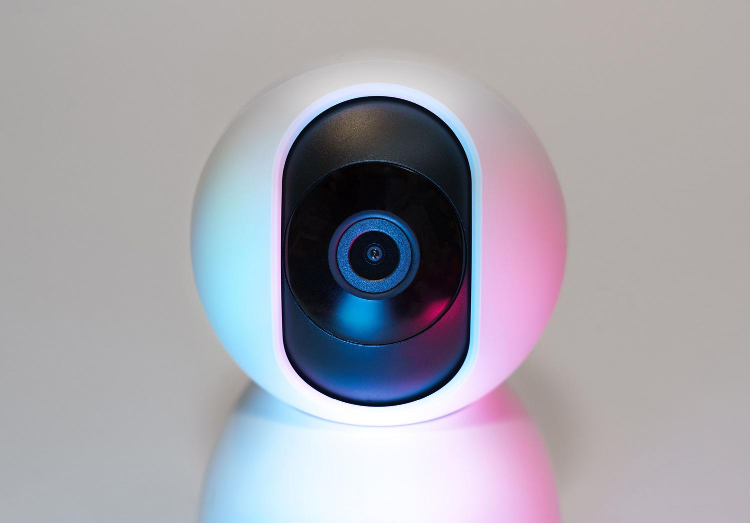 Cámara de seguridad IP con iluminación tecnológica en tonos azules y rosas, simbolizando la interconexión y el riesgo de hackeo en redes digitales.