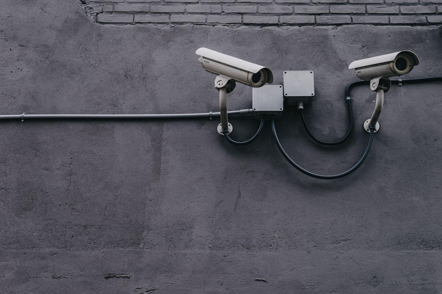 Cámaras de seguridad tipo bala instaladas en una pared de concreto con cableado visible, representando la infraestructura física y digital vulnerable de las redes IoT.