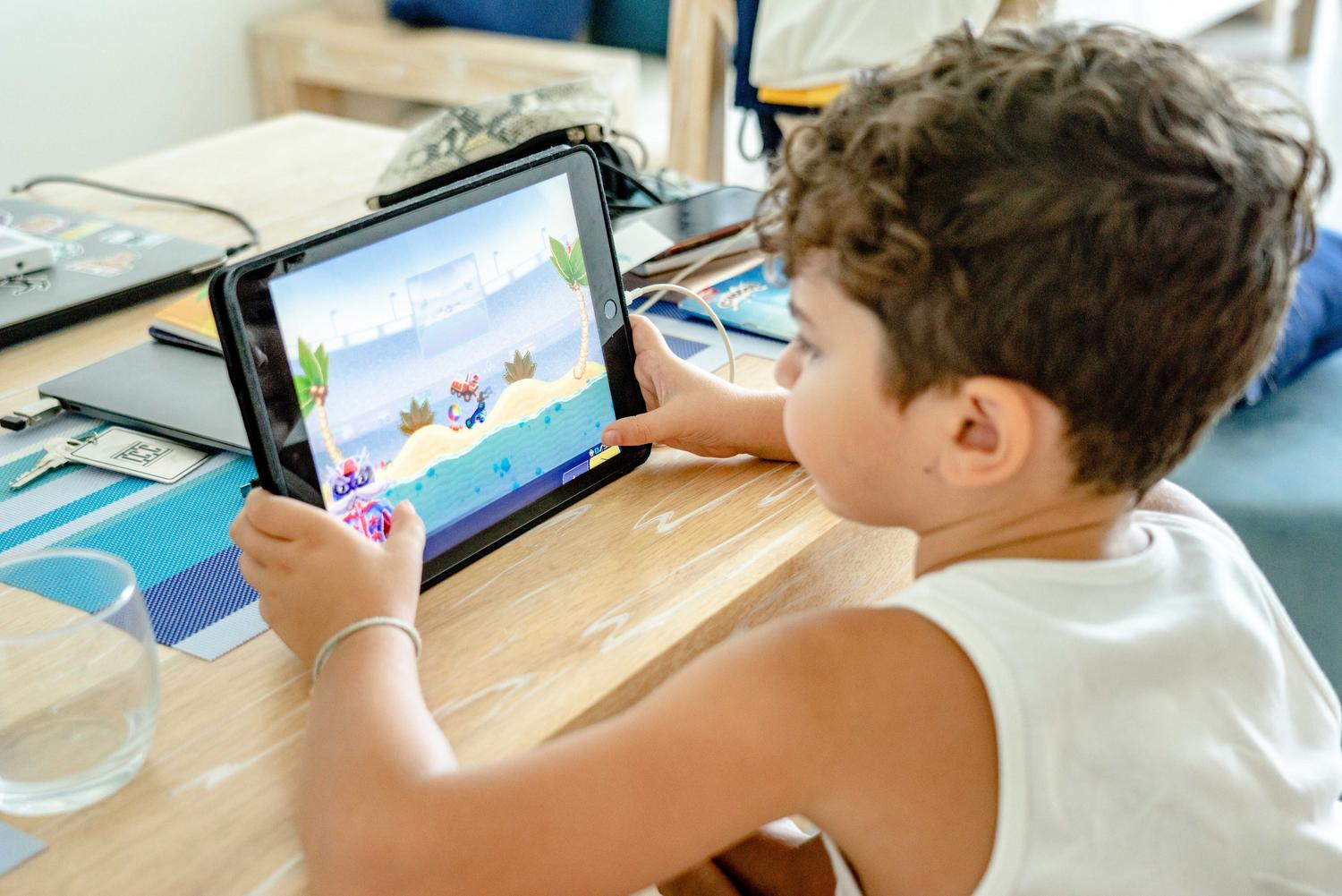 Un niño concentrado jugando a un videojuego en una tablet, ejemplificando el rendimiento gráfico y de gaming del chip.