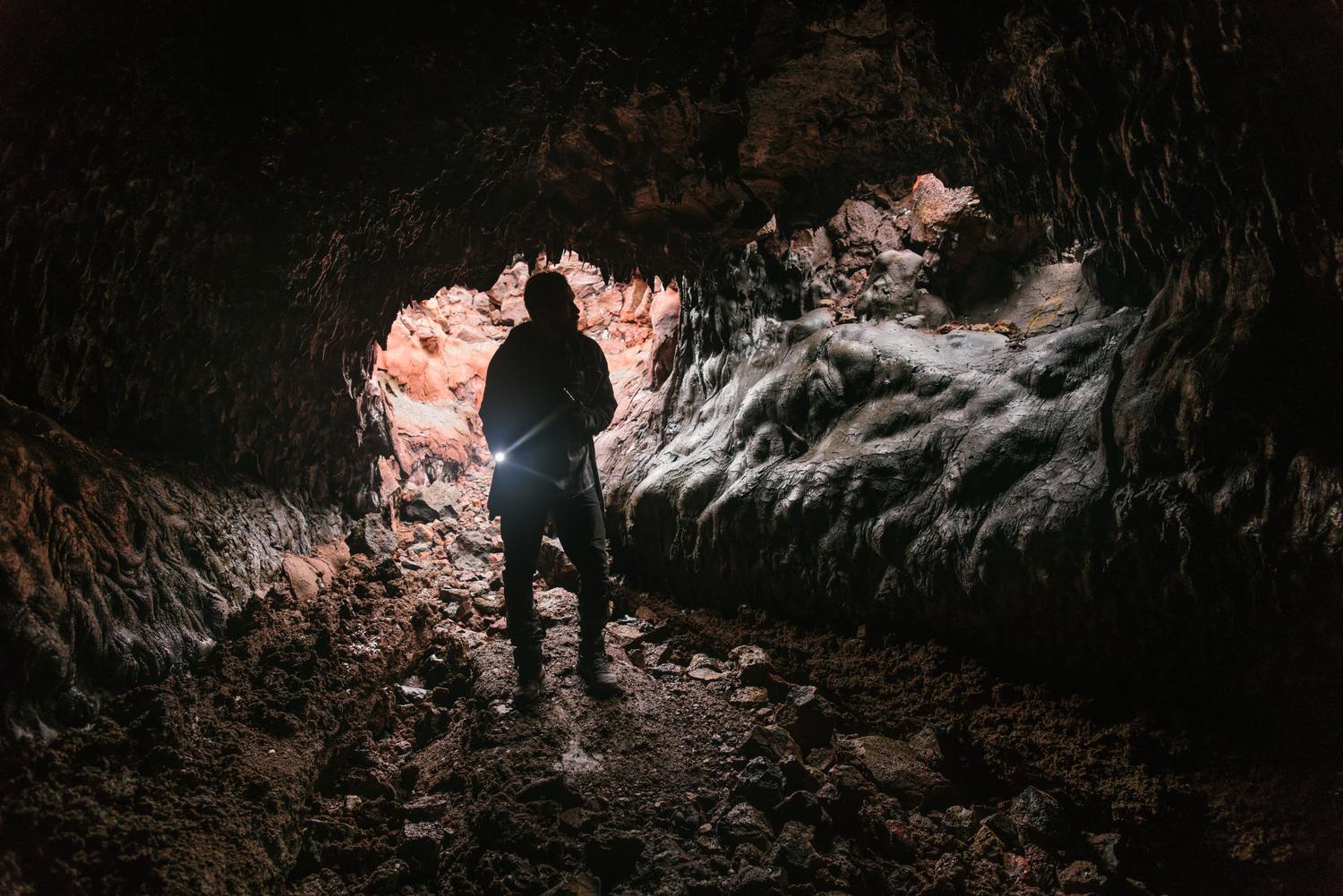 Silueta de un explorador navegando por una cueva oscura utilizando una linterna, ilustrando la navegación por el sistema subterráneo