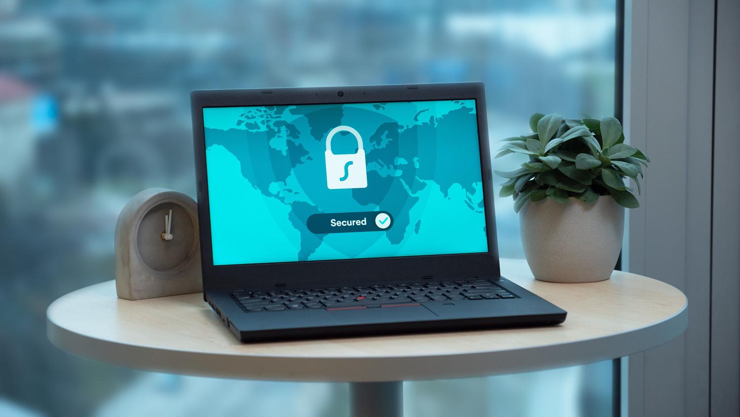 Ordenador portátil mostrando un candado de seguridad y un mapa mundial, representando una conexión VPN segura y global.