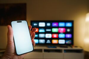 Persona utilizando un smartphone como mando a distancia para controlar una Smart TV en un salón acogedor.