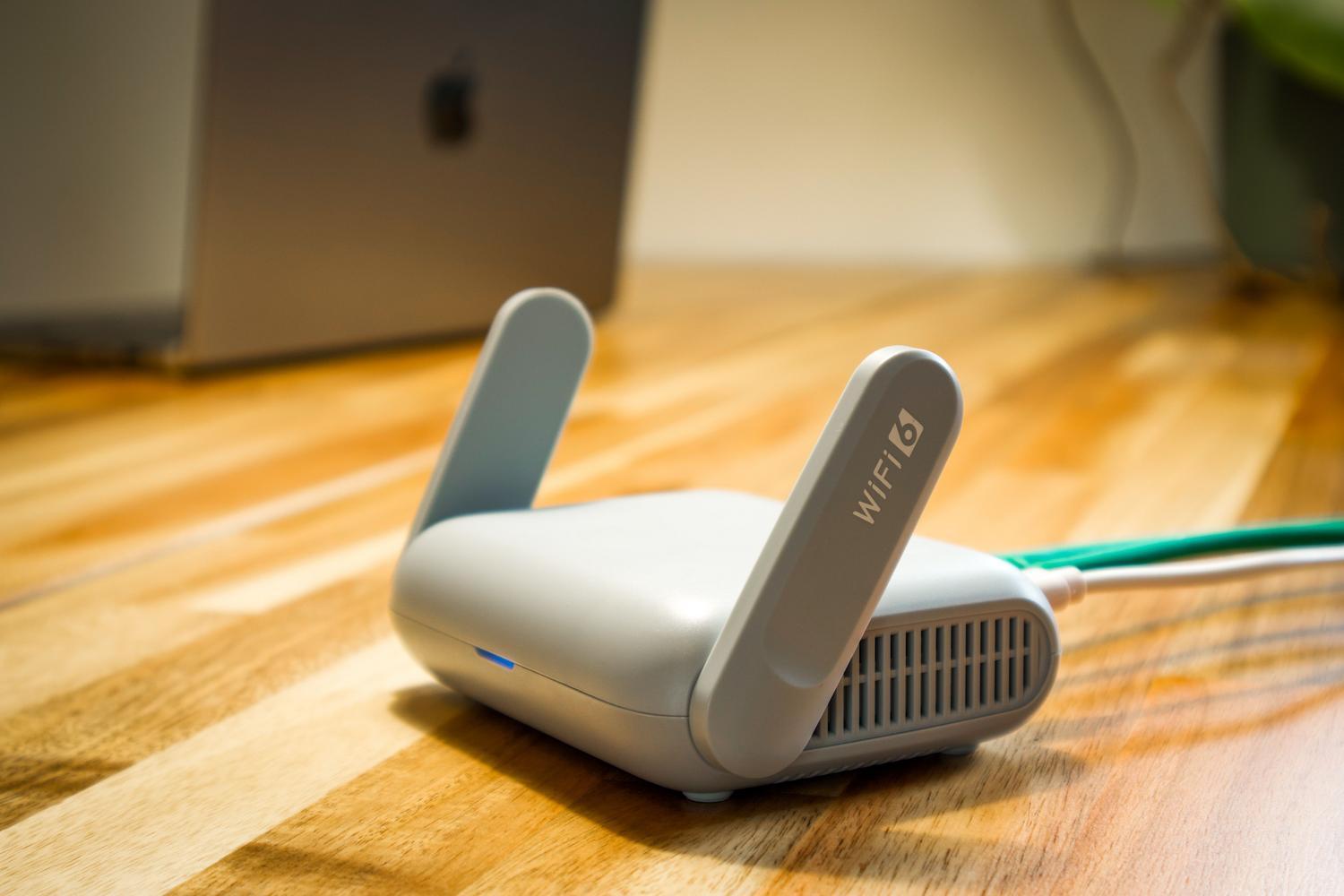 Router WiFi moderno sobre una mesa de madera, ideal para ilustrar la gestión técnica de la conexión en el hogar