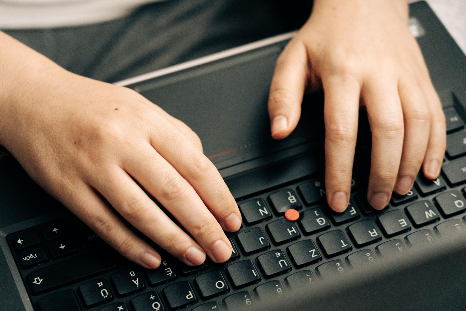 Primer plano de manos utilizando el teclado de un ordenador portátil, ideal para ilustrar los atajos de teclado Ctrl+C y Ctrl+V.