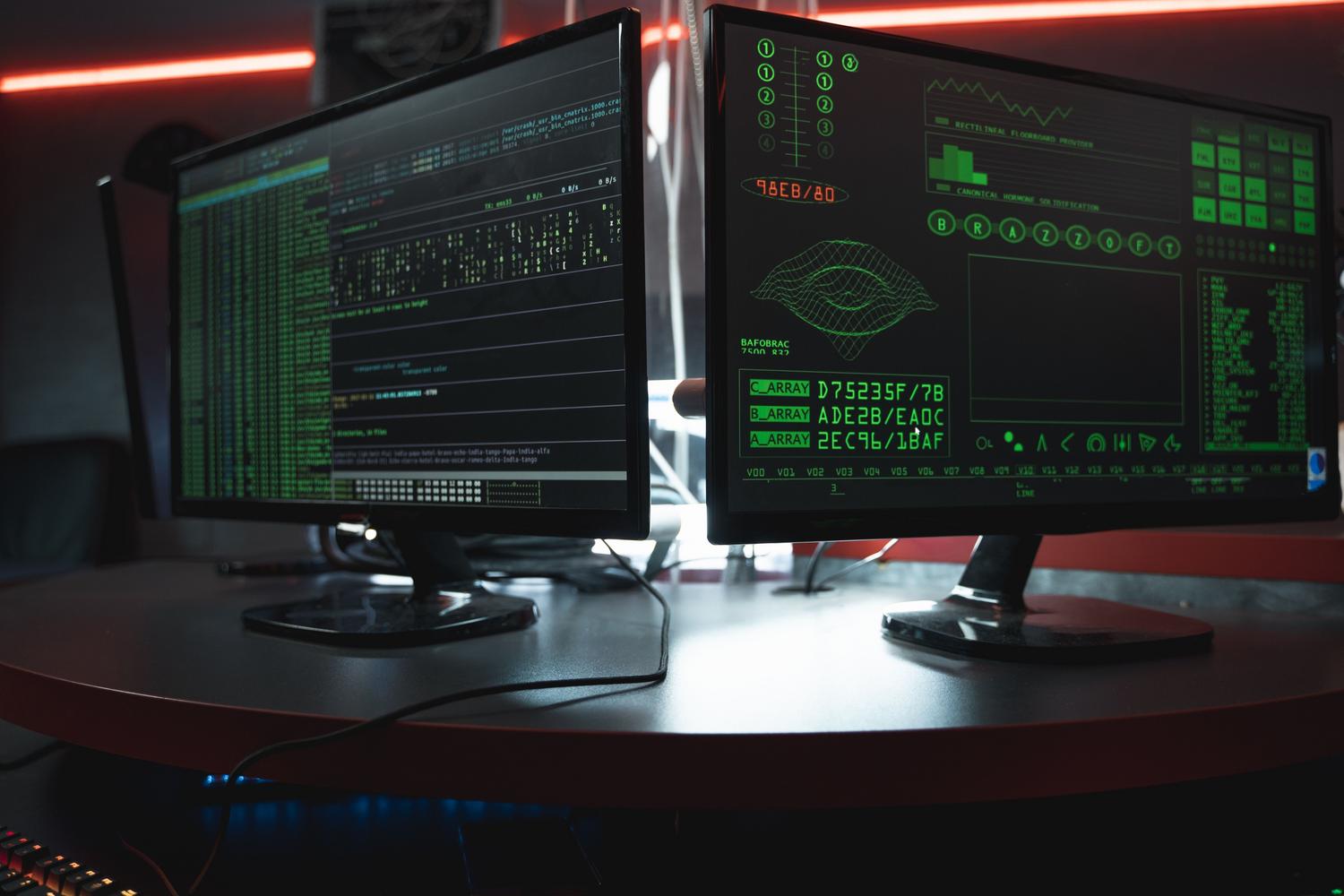 Monitores de ordenador en una habitación oscura con código verde, simbolizando el origen digital y anónimo de los creepypastas.