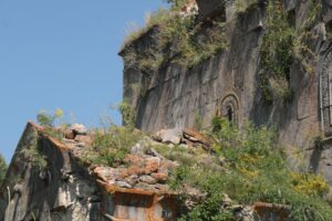 Ruinas antiguas de piedra cubiertas por vegetación exuberante y musgo, representando la Era de la Calamidad donde la naturaleza reclama el reino.
