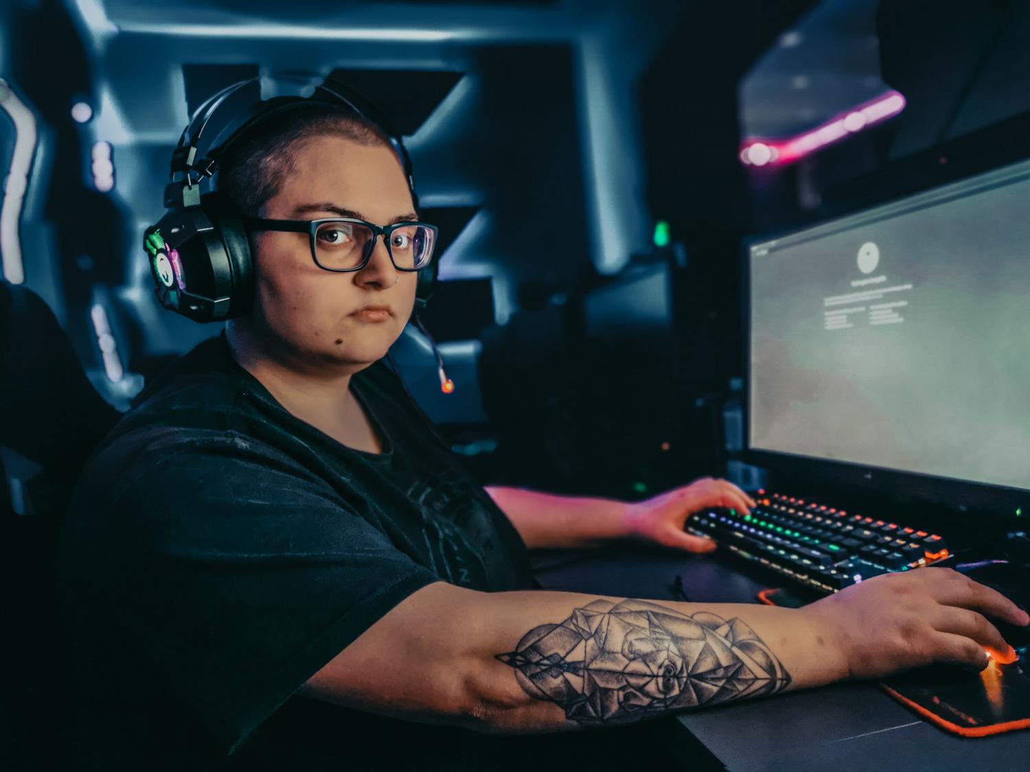 Gamer utilizando un setup de PC avanzado con teclado mecánico y auriculares RGB para jugar en línea.