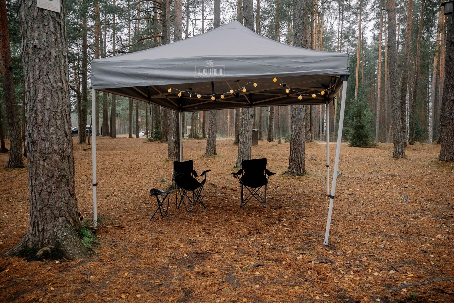 Campamento acogedor en el bosque con tienda y sillas, representando la filosofía cozy y social de Aniimo.