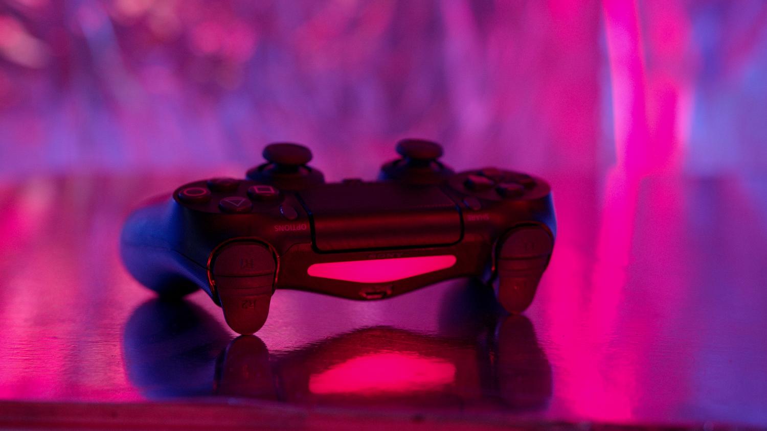Mando de PlayStation 4 con iluminación neón rosa y púrpura, resaltando la estética gamer moderna.