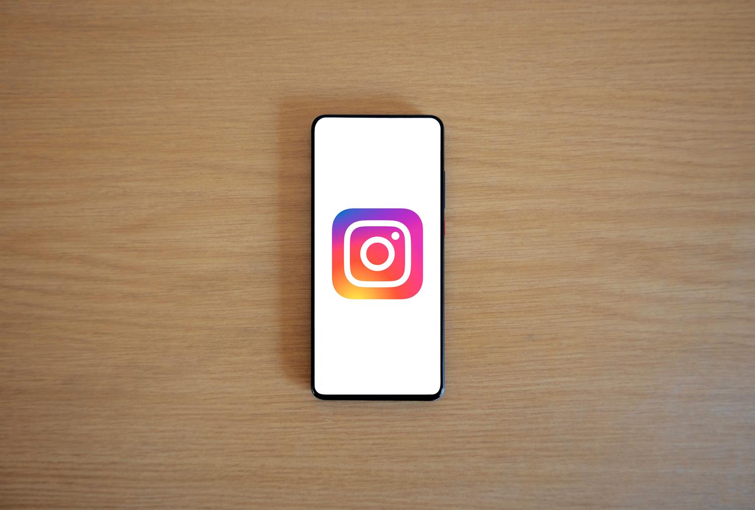 Un smartphone con el logotipo de Instagram en pantalla sobre una superficie de madera, ideal para introducir el tema de la personalización de la plataforma.