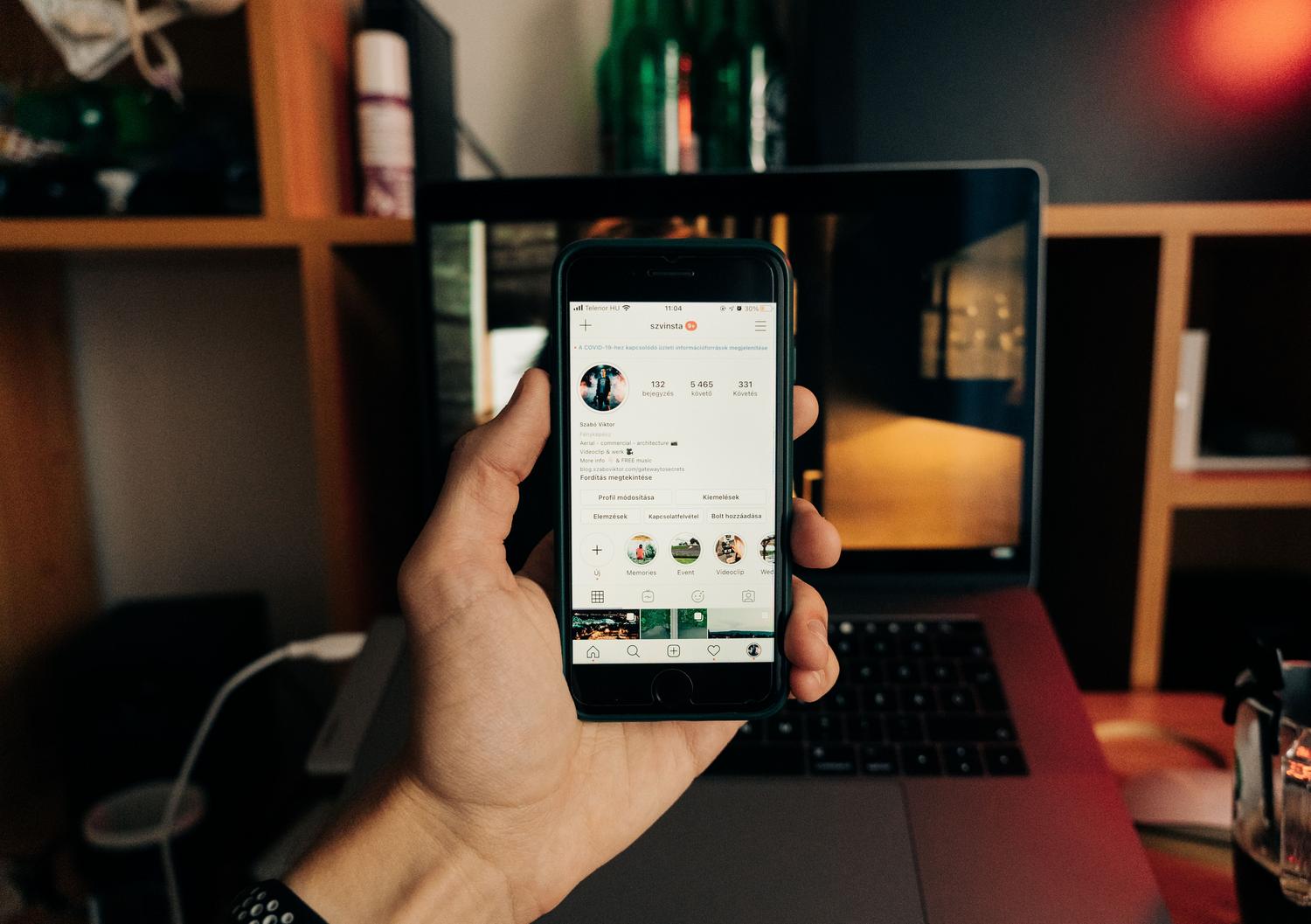 Mano sosteniendo un teléfono con la aplicación de Instagram abierta, enfocándose en la interacción del usuario con su presencia digital.