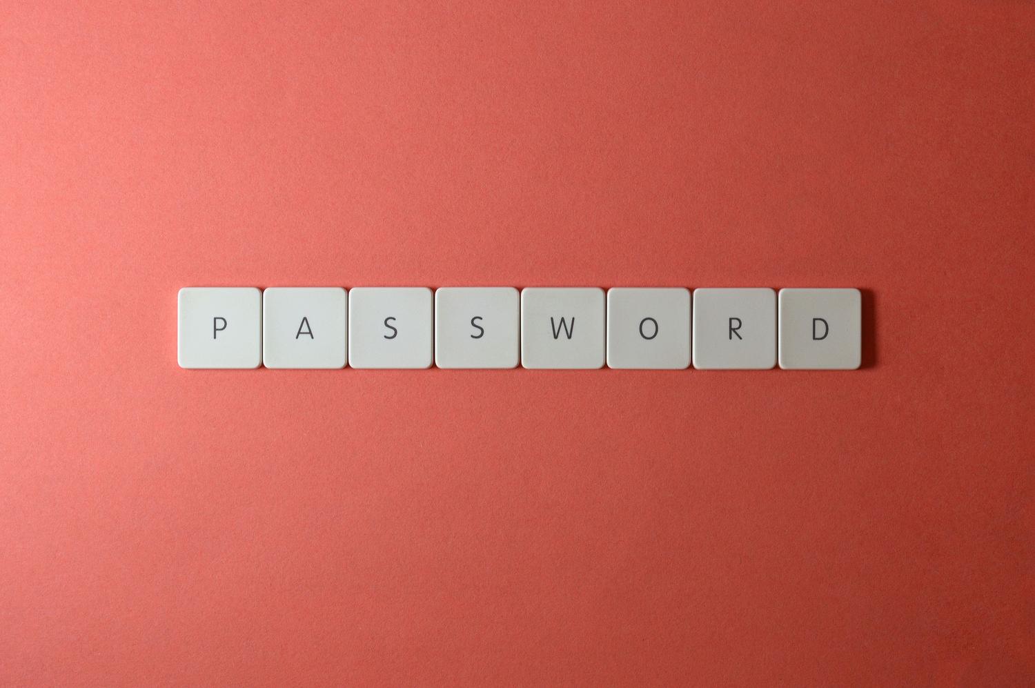 Teclas de teclado blancas formando la palabra PASSWORD sobre un fondo coral, representando la seguridad de las contraseñas.