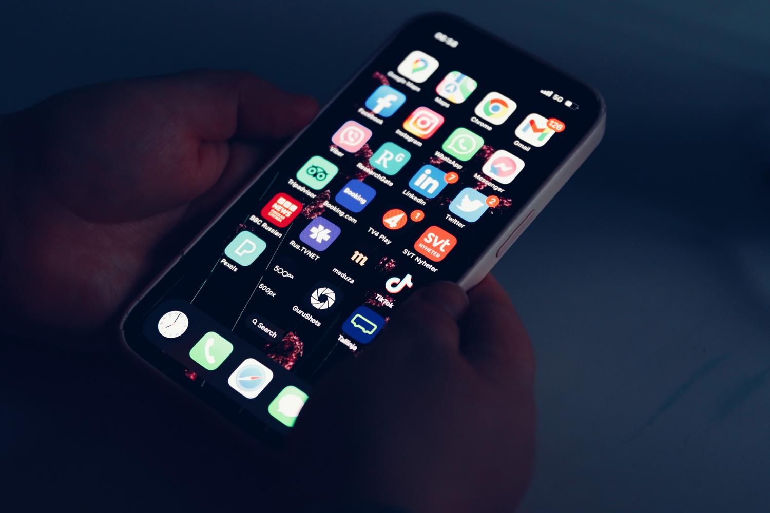 Primer plano de manos sosteniendo un smartphone con aplicaciones, representando la gestión de chats efímeros en dispositivos móviles.