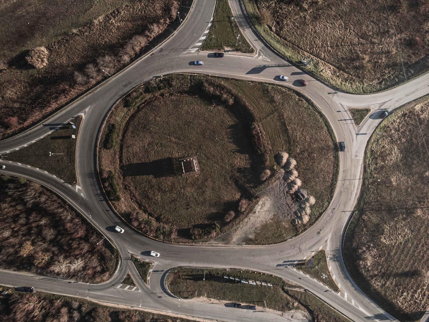 Vista aérea de una rotonda de tráfico en un paisaje rural, representando la recurrencia de rotondas que dio nombre a la canción Roundabout.
