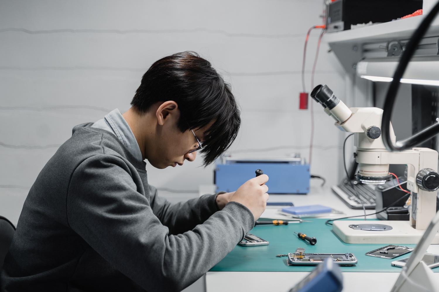 Técnico especializado reparando componentes electrónicos de precisión con un microscopio