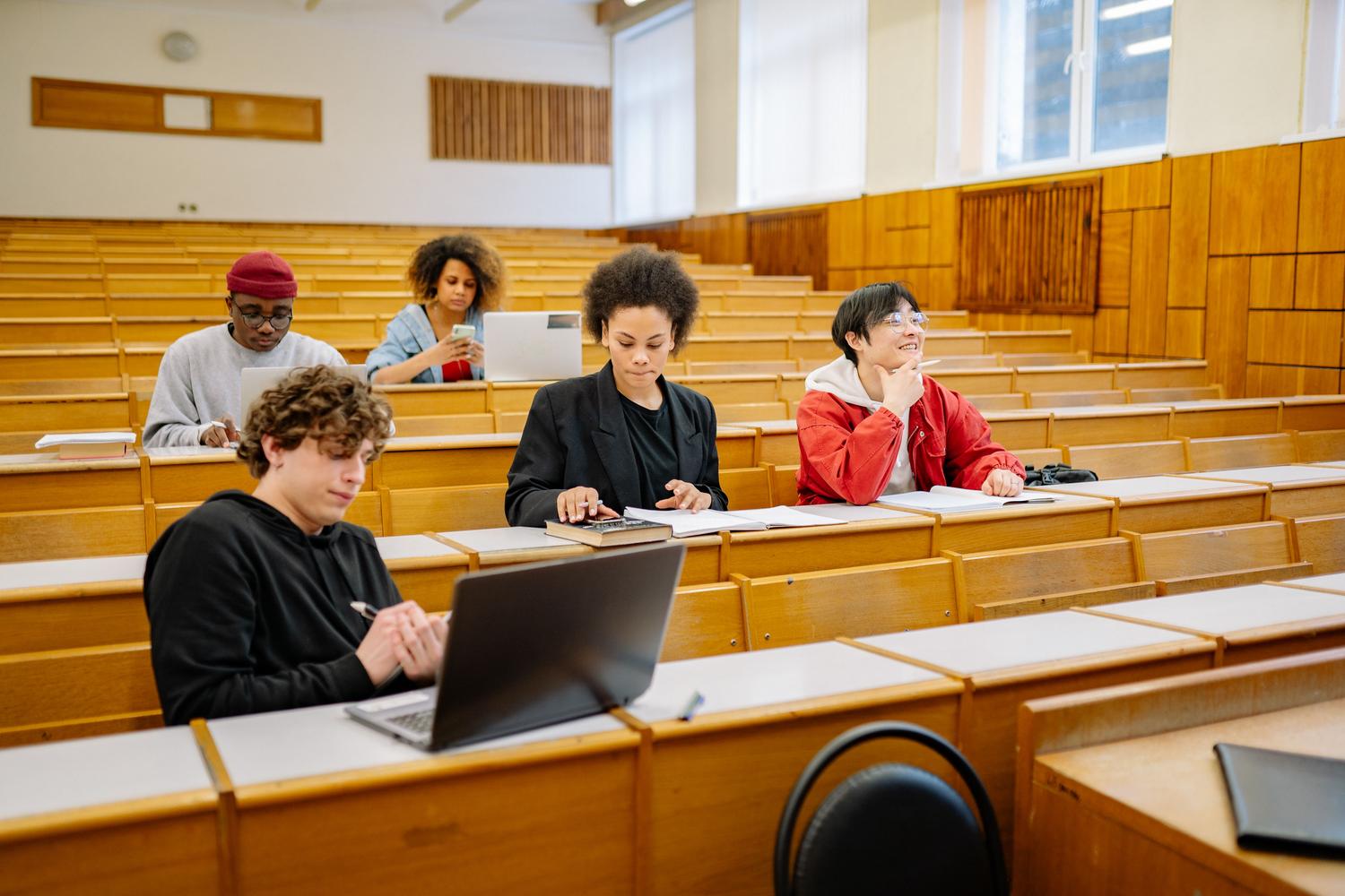 Grupo diverso de estudiantes universitarios utilizando tecnología en un aula moderna.