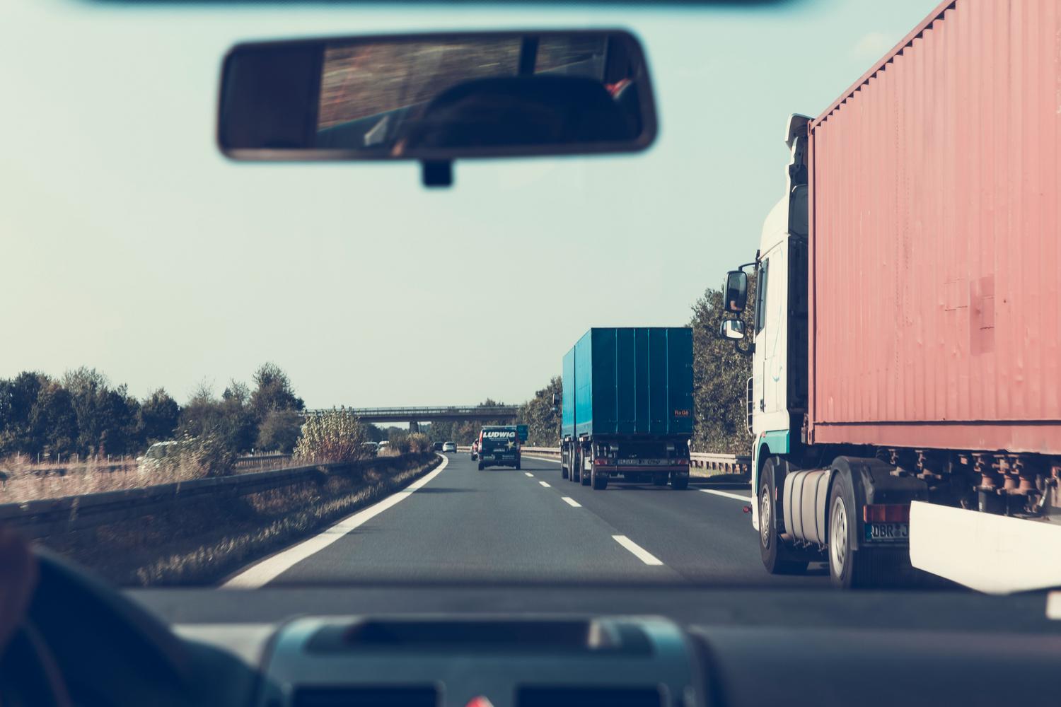 Vista a través del espejo retrovisor de camiones circulando por una autopista en Alemania, representando los ajustes de espejos del simulador.