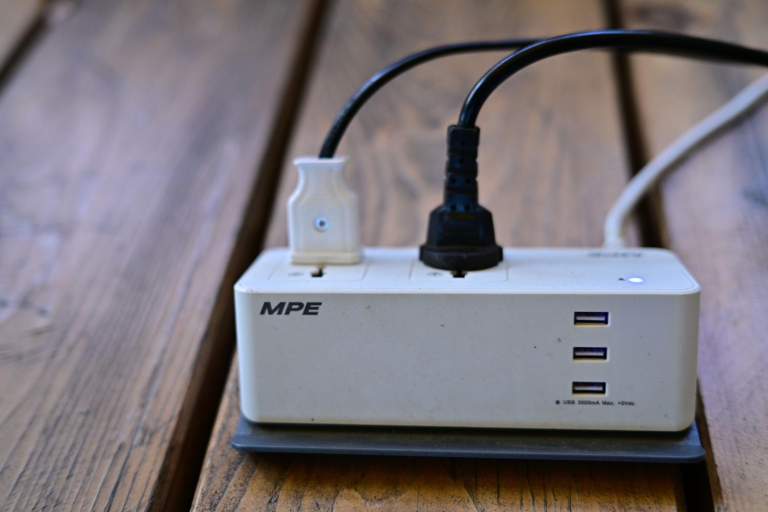 Regleta con múltiples puertos USB y cables conectados sobre una superficie de madera
