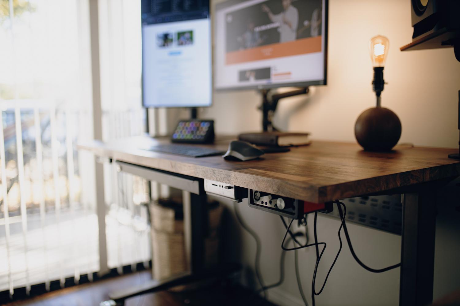 Espacio de trabajo en casa limpio y eficiente con ordenador y escritorio elevable sin cables a la vista