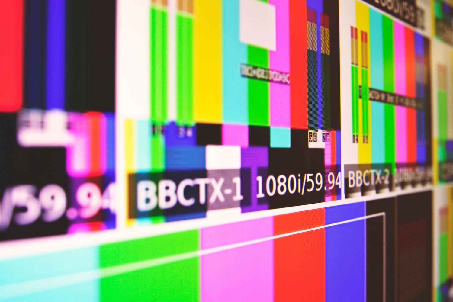 Primer plano de una pantalla con barras de color y patrones de prueba técnicos, mostrando la resolución 1080i.