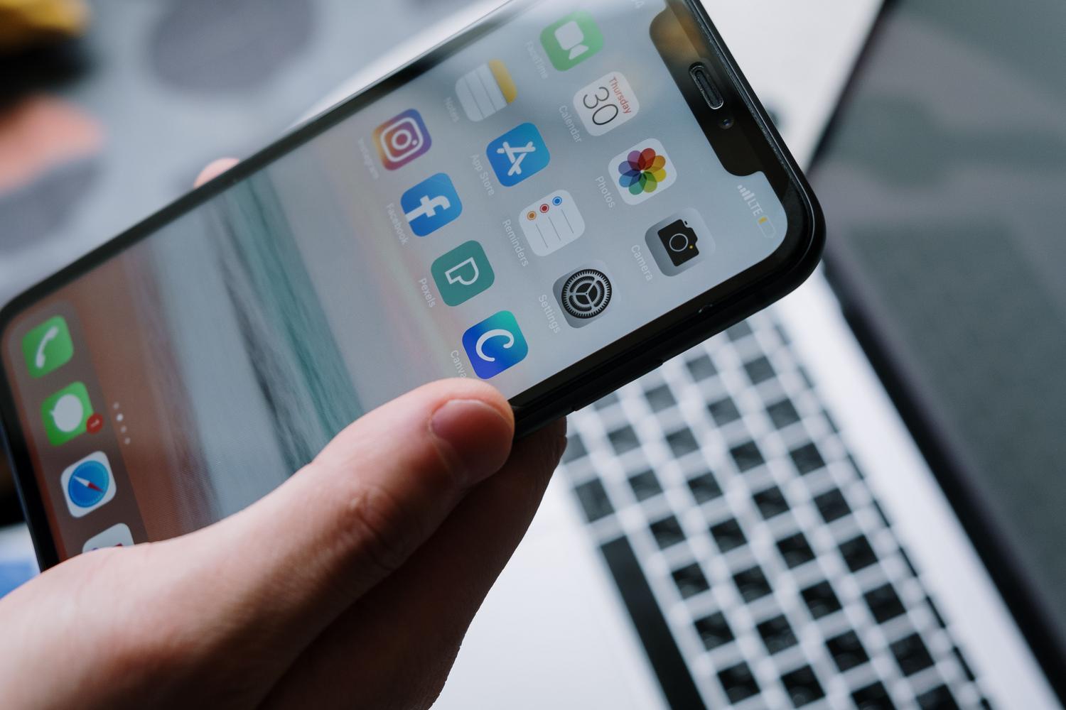Smartphone junto a un ordenador portátil, representando la sincronización de copias de seguridad de iCloud o iTunes