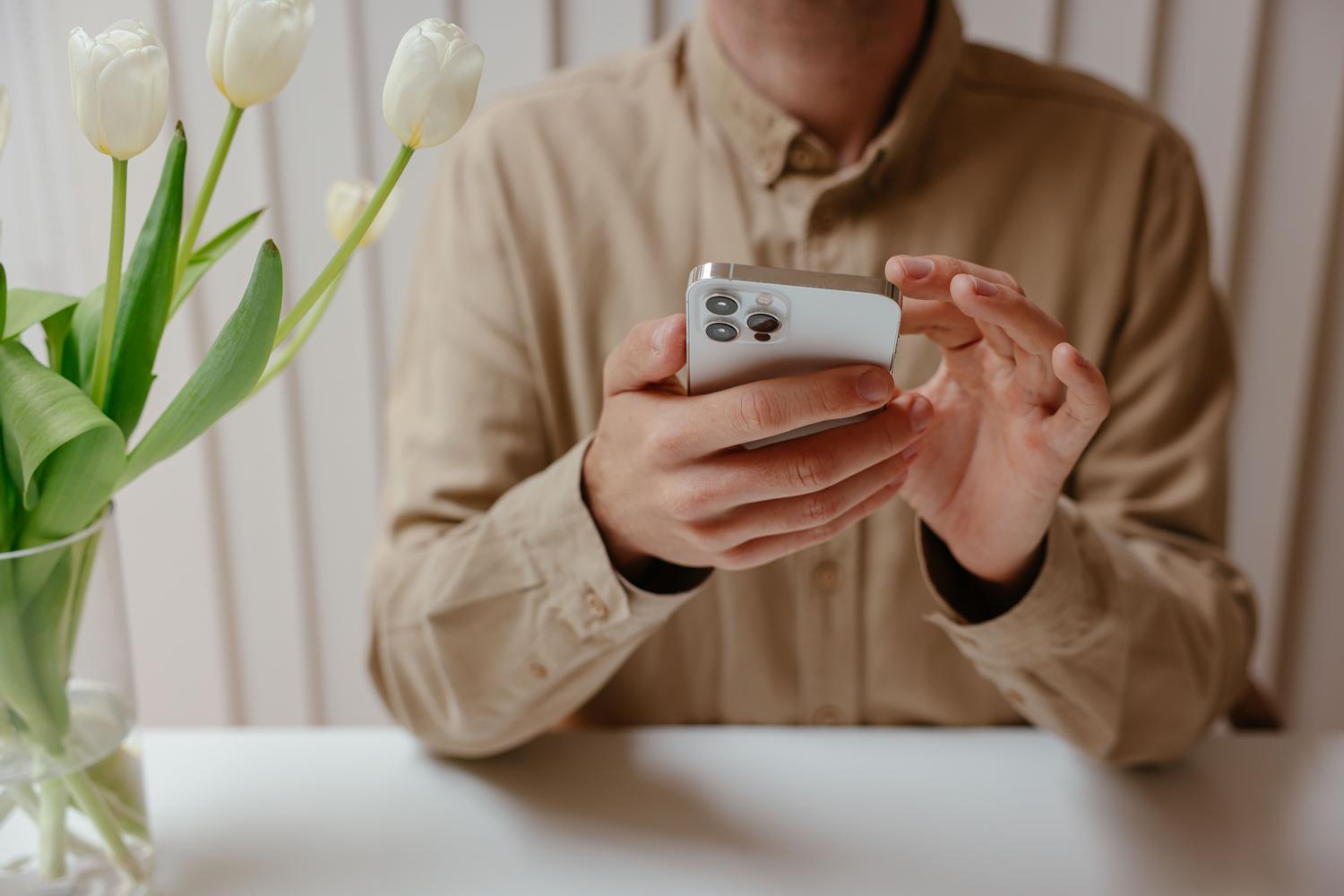 Persona interactuando con un iPhone en un escritorio minimalista y moderno, representando la gestión tecnológica