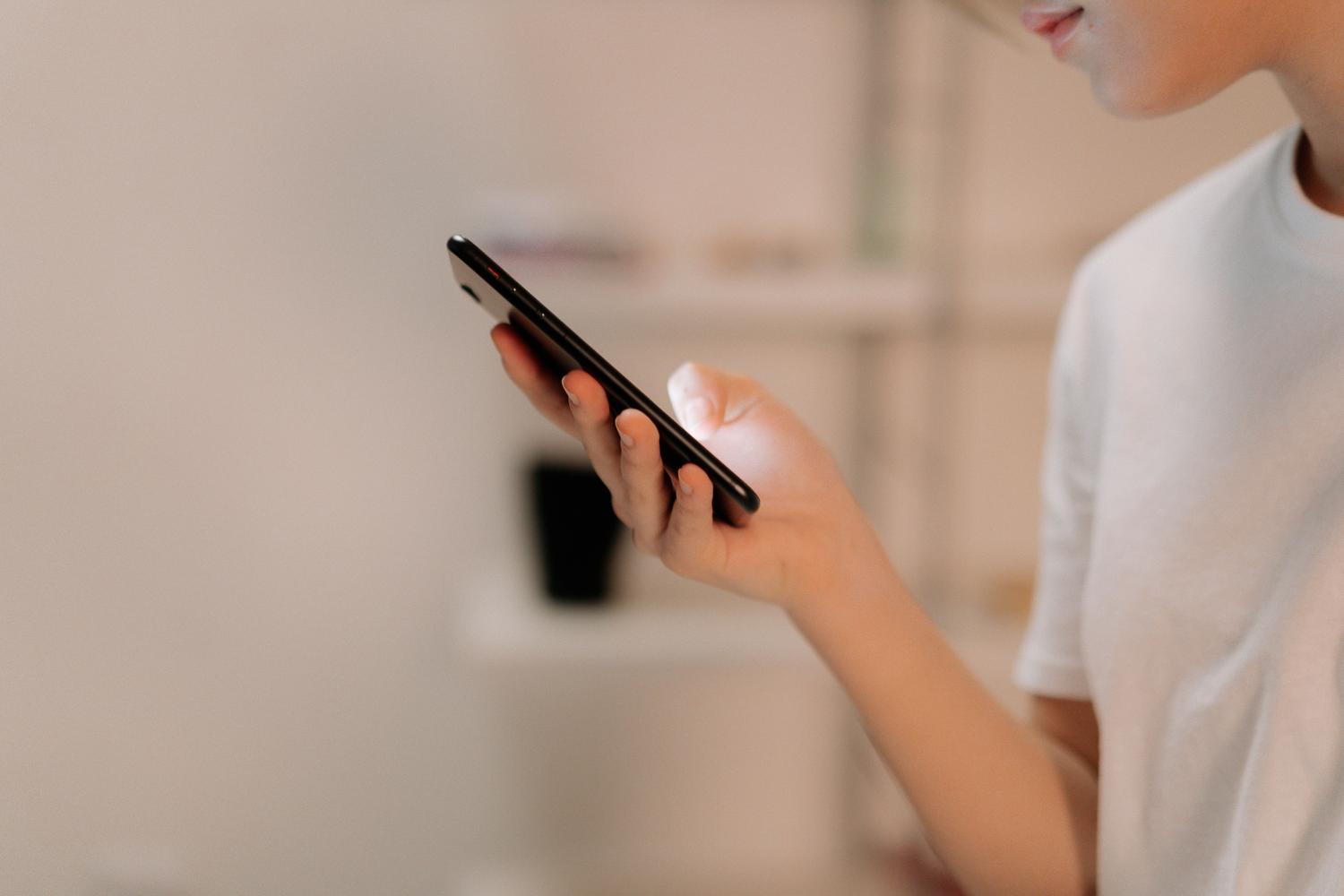 Persona utilizando un smartphone en un entorno interior, ilustrando la navegación por aplicaciones móviles