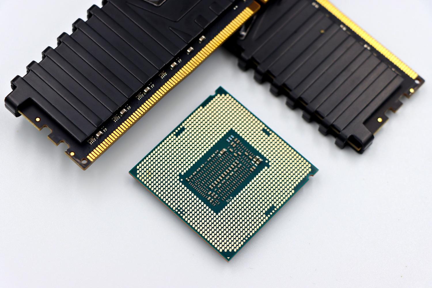 Primer plano de un procesador CPU y módulos de memoria RAM sobre fondo blanco.