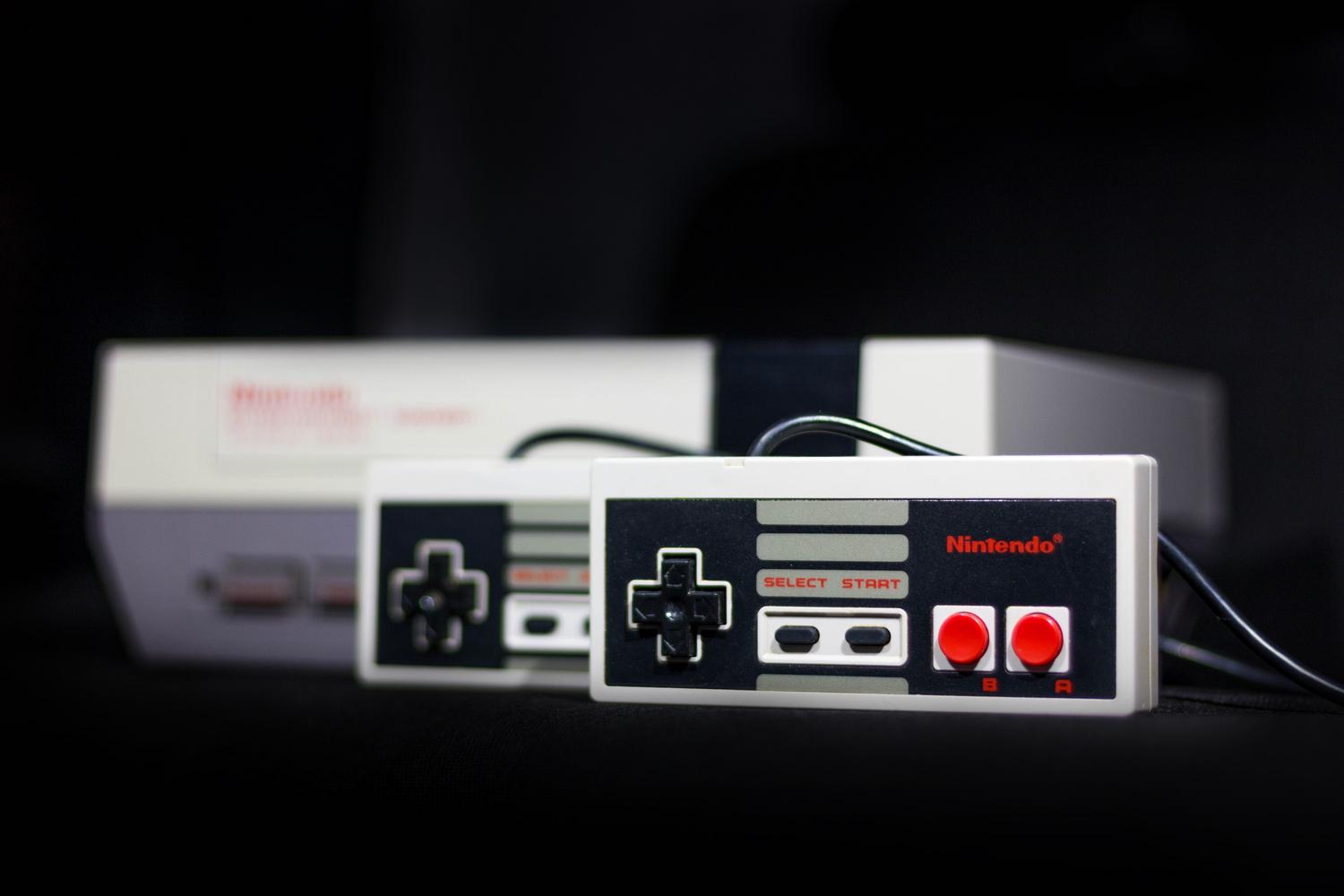 Primer plano de una consola Nintendo NES clásica y sus mandos, símbolo fundamental de la era de los videojuegos domésticos de los 80.