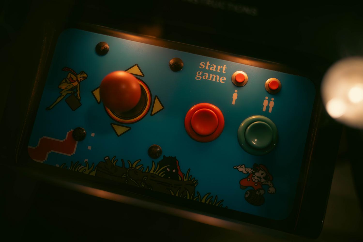Detalle de los controles de una máquina arcade retro con joystick y botones, representando la interacción táctil del ocio digital temprano.
