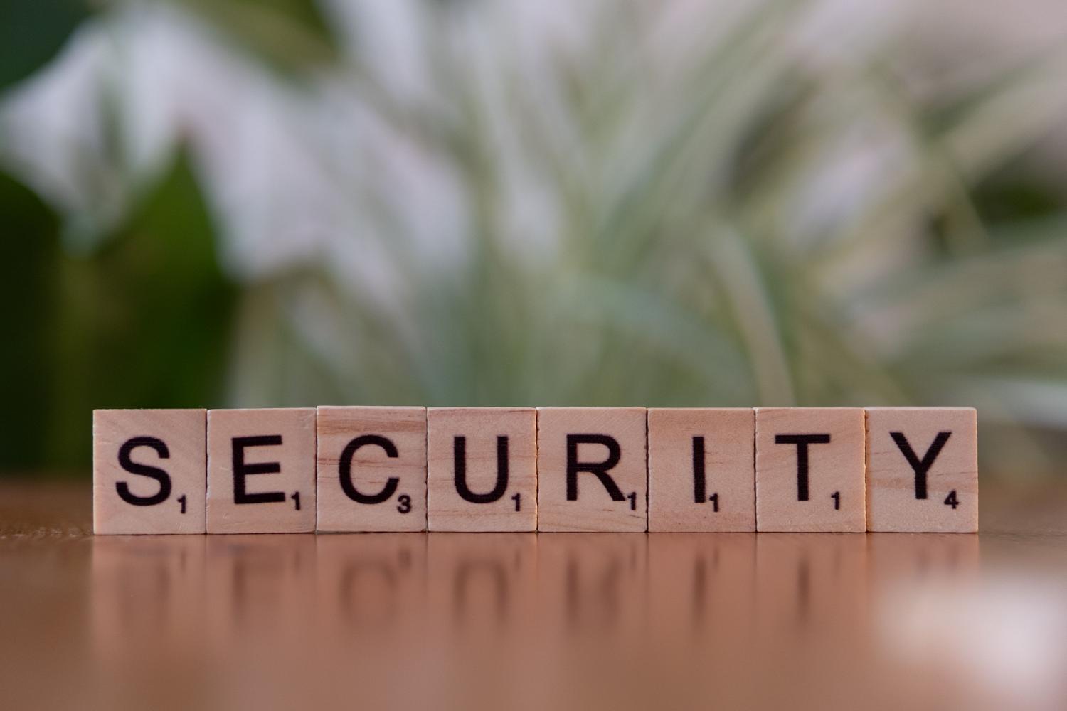 Fichas de madera de Scrabble formando la palabra SECURITY sobre un fondo natural, representando la base de la seguridad digital.