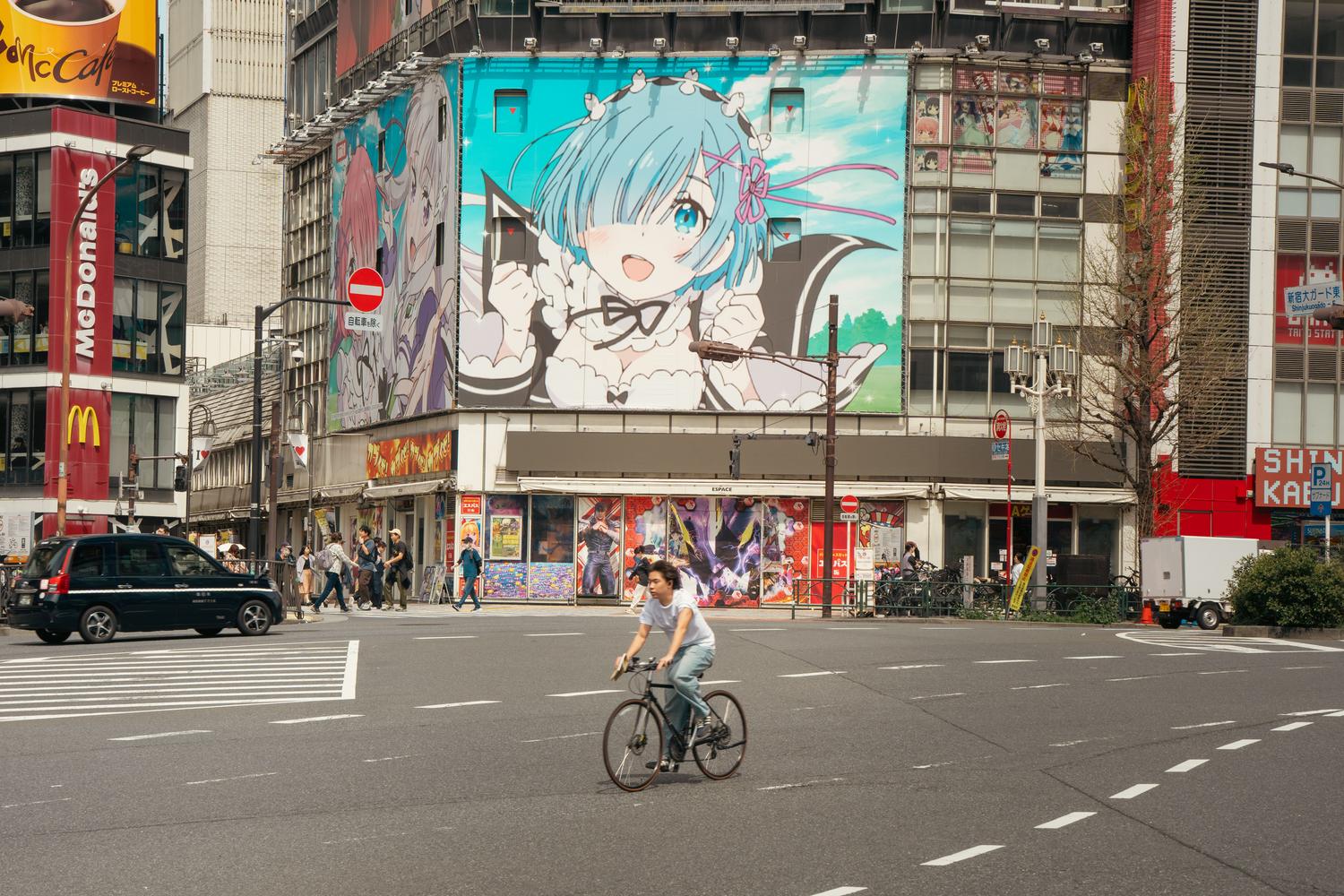 Calle de Tokio con un mural gigante de un personaje de anime, integrando la cultura otaku en el paisaje urbano.