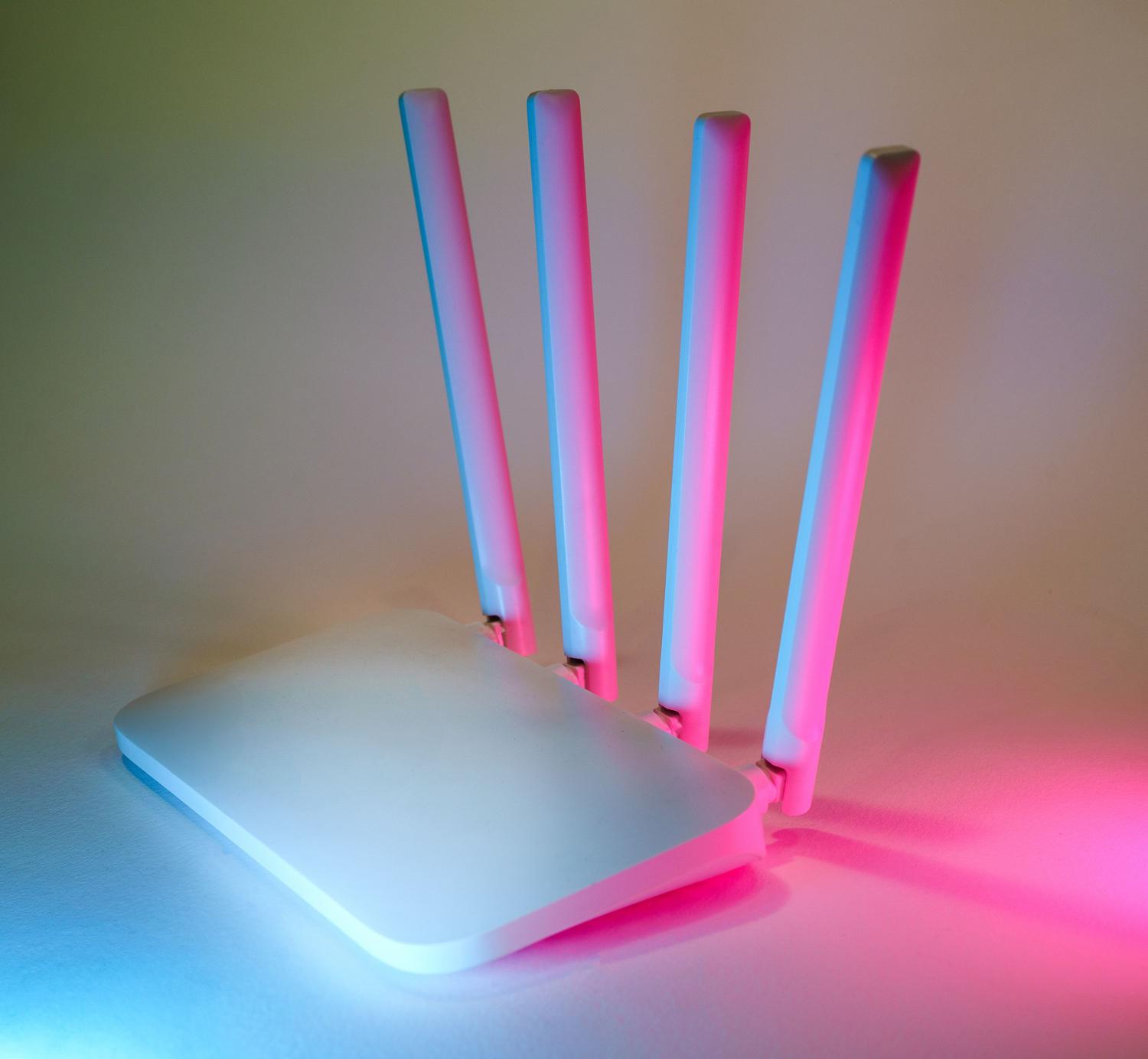 Router wireless moderno di fascia alta con antenne e luci al neon blu e rosa, a testimonianza dell'avanzata tecnologia WiFi 7. Router wireless moderno di fascia alta con antenne e luci al neon blu e rosa, a testimonianza dell'avanzata tecnologia WiFi 7.