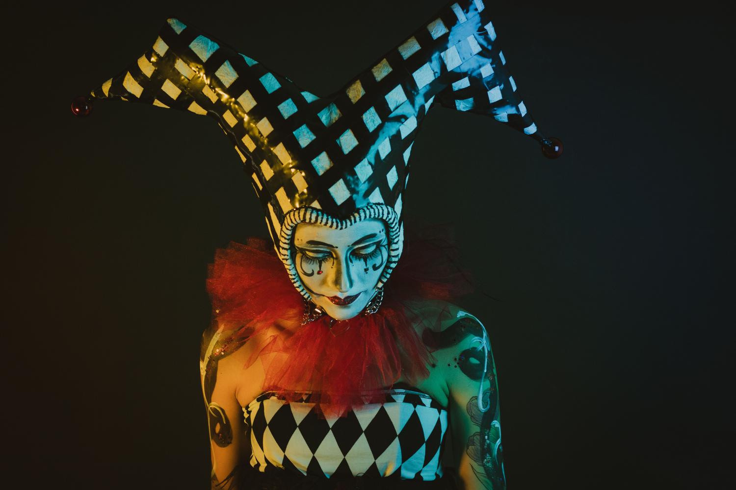 Retrato teatral y grotesco de un bufón con maquillaje dramático y luces contrastadas, representando el estilo del Circus Metal.