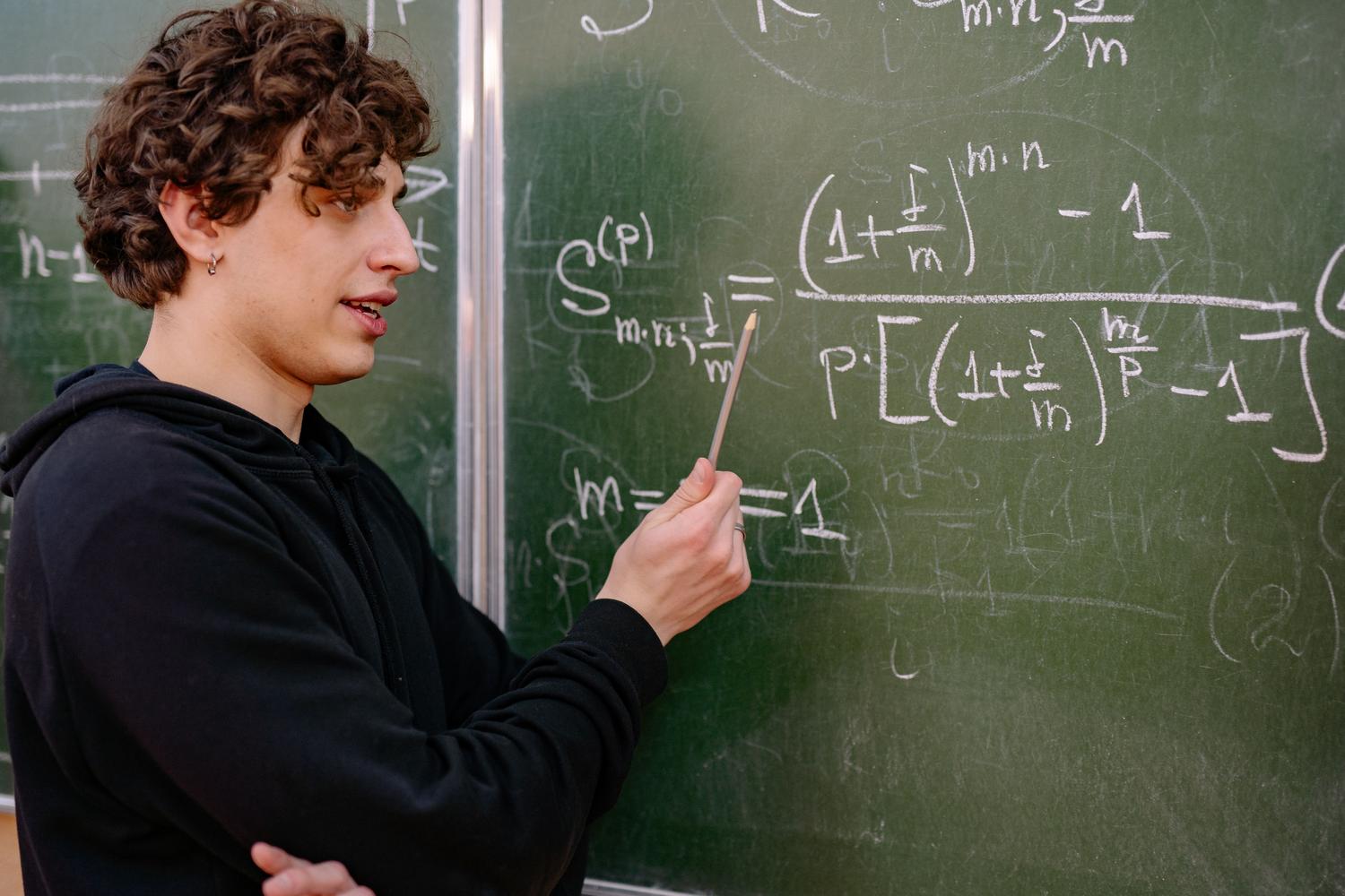 Profesor explicando ecuaciones matemáticas complejas en una pizarra de aula universitaria, ideal para ilustrar la base teórica de la estadística.