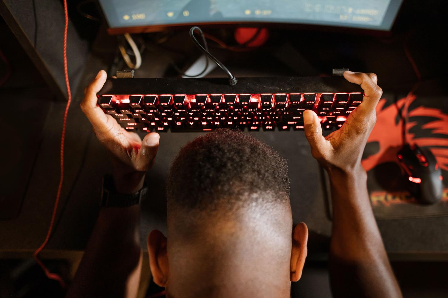 Gamer frustrado sosteniendo su teclado, ilustrando la molestia causada por bugs en el software.