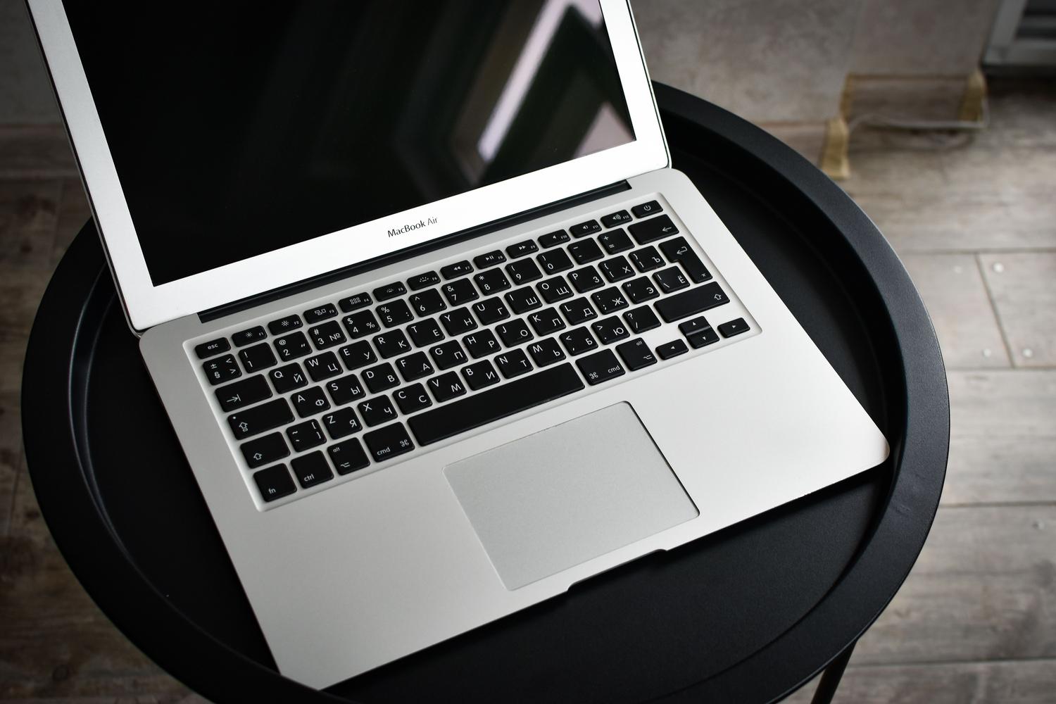 Una MacBook elegante sobre una mesa negra, representando el entorno de escritorio de macOS donde se instala la app de Gemini.
