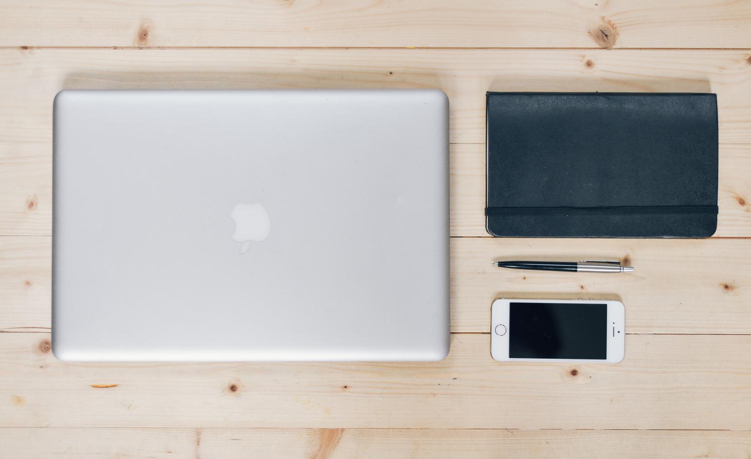 Escritorio organizado con portátil y smartphone, ilustrando la productividad y la gestión de comunicaciones en el ecosistema Apple.