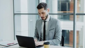 Hombre de negocios trabajando con un ordenador portátil en una oficina moderna y minimalista, representando el perfil profesional y premium del Googlebook.