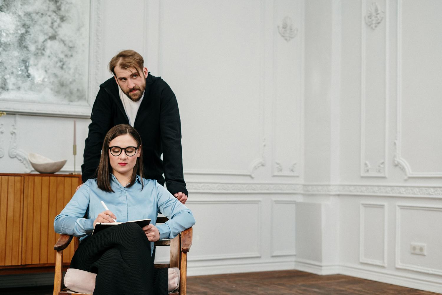 Un hombre y una mujer profesionales manteniendo una conversación de consultoría en una oficina moderna, representando las habilidades humanas de empatía e inteligencia emocional.