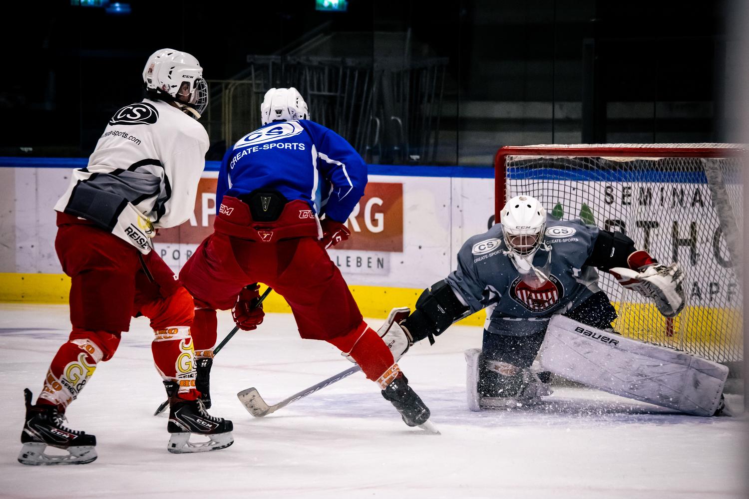 Momento dramático de un partido de hockey sobre hielo con jugadores atacando la portería.