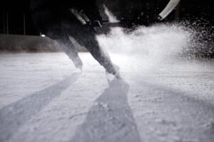 Jugador de hockey sobre hielo en plena acción generando una nube de hielo en la pista.