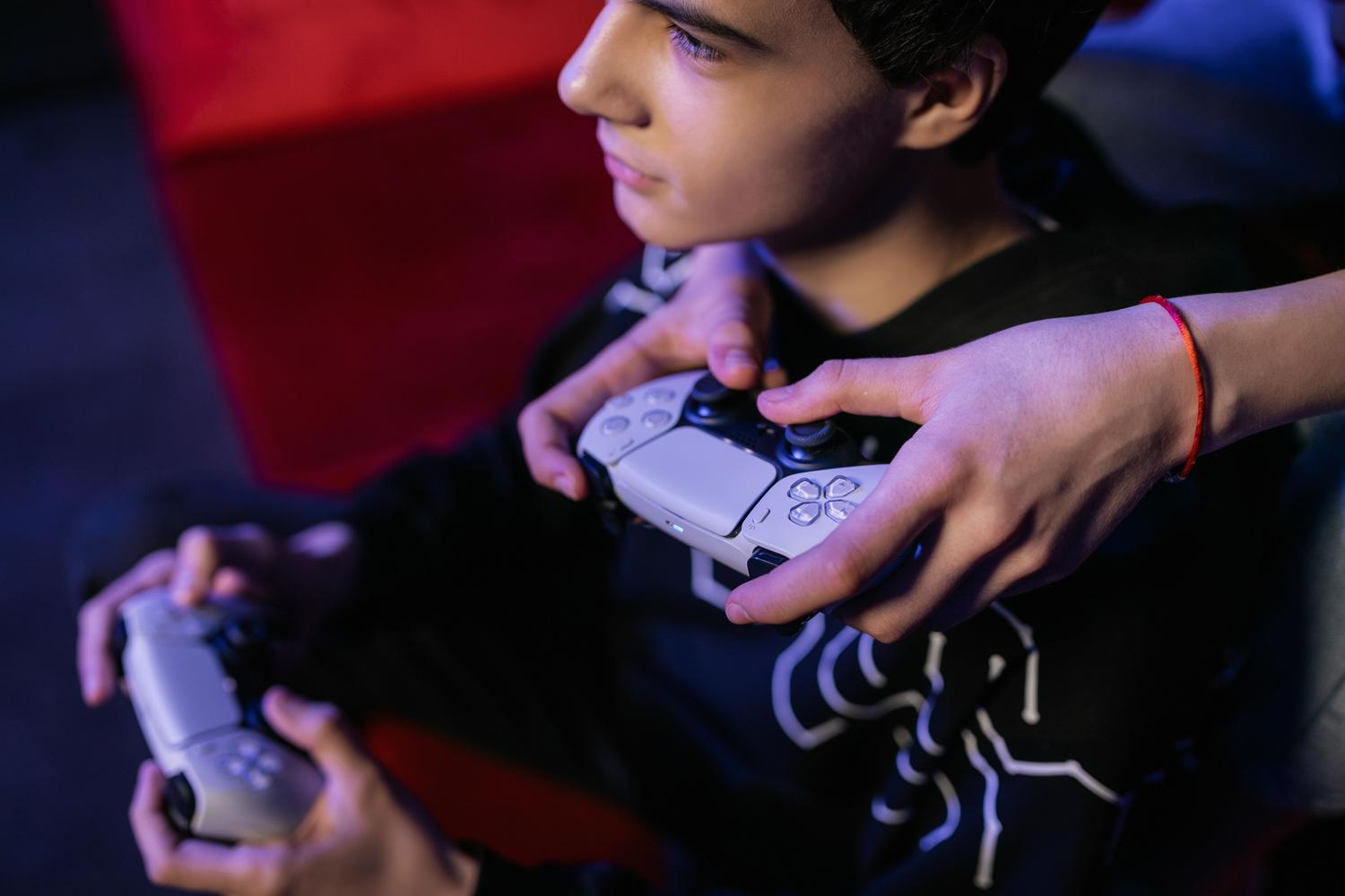 Dos personas jugando videojuegos juntas con mandos modernos, representando la experiencia conectada de NHL 27.