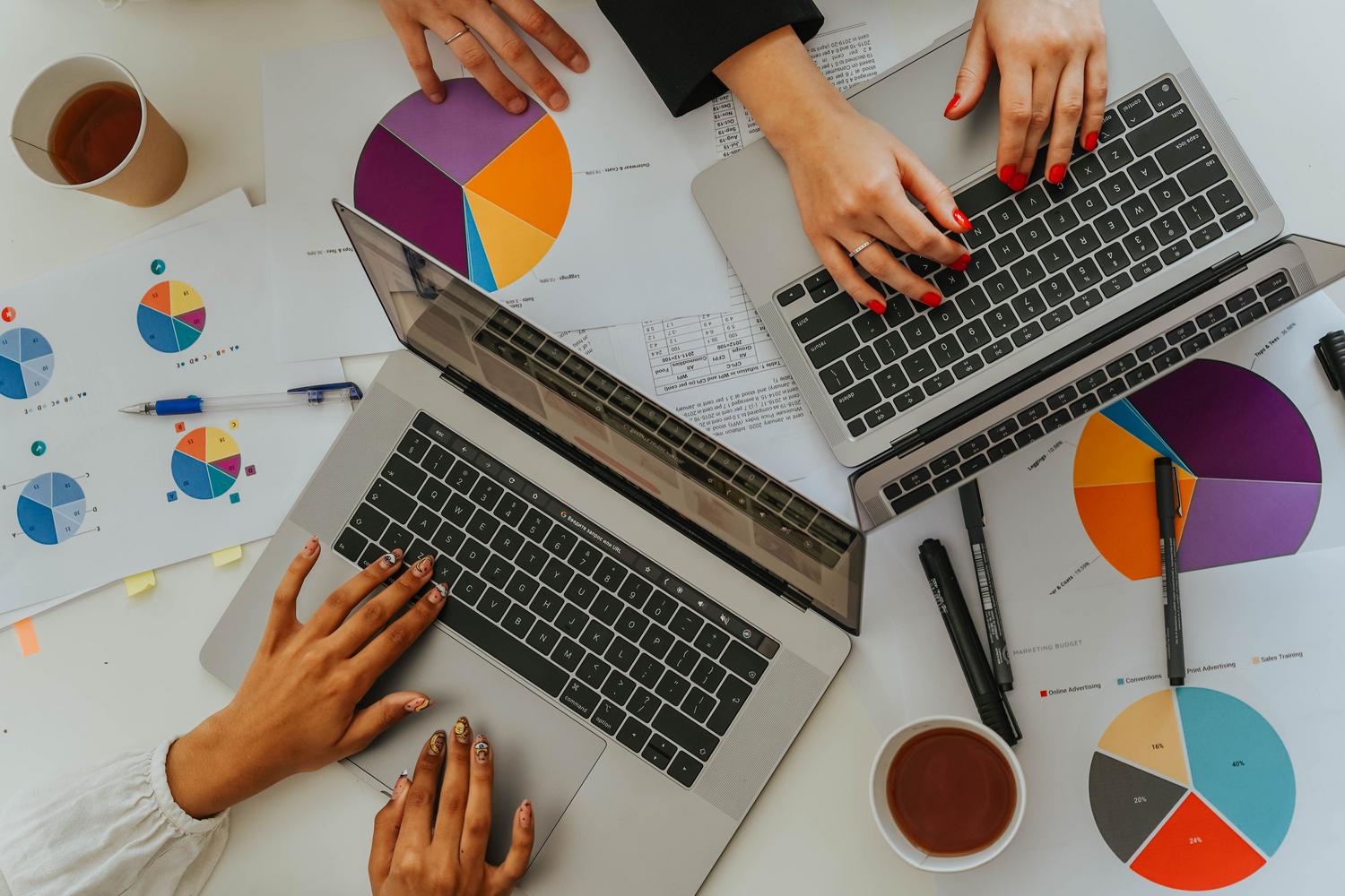 Equipo de trabajo analizando gráficas y tablas de datos en portátiles durante una reunión de business intelligence.