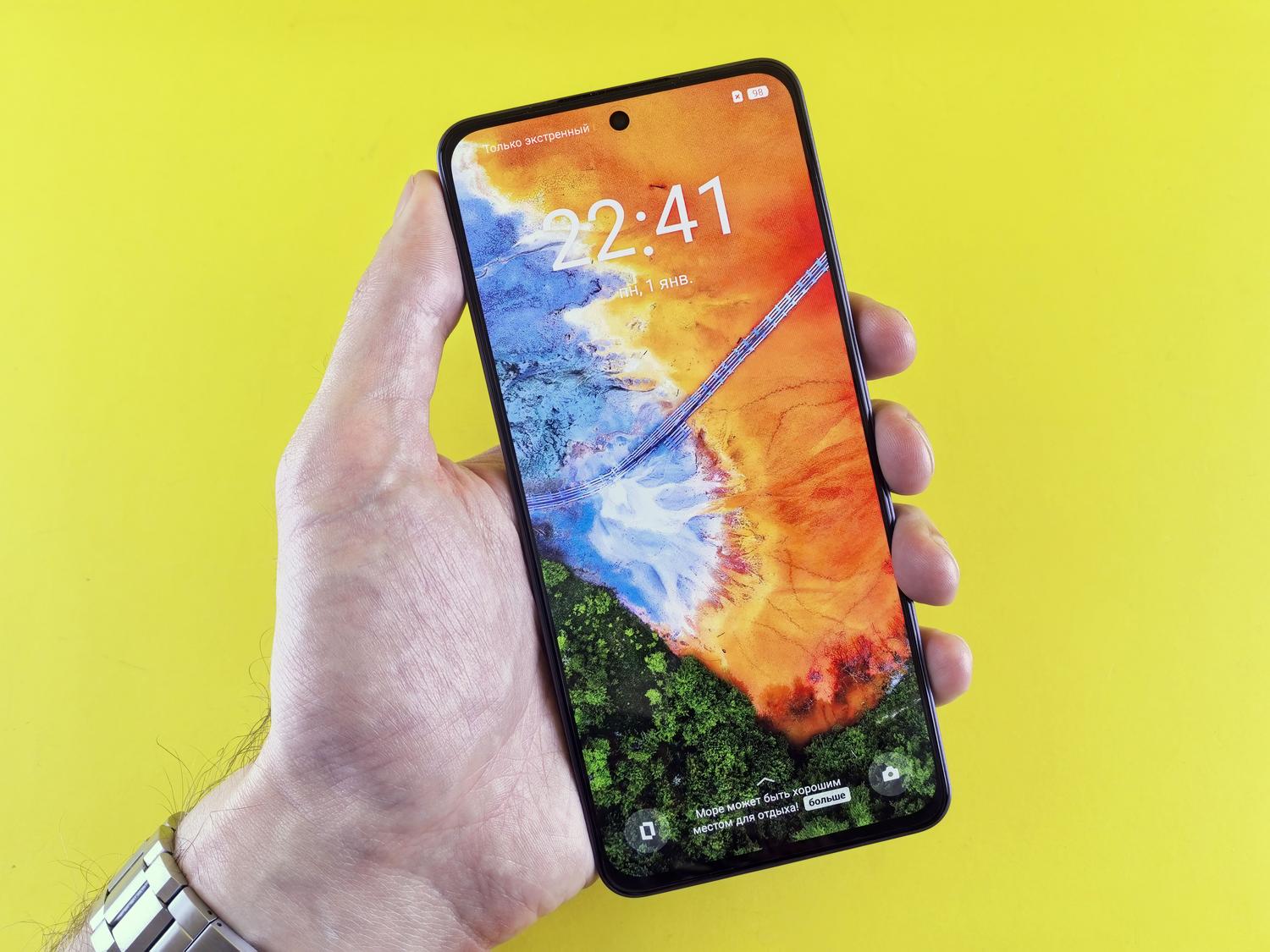 Primer plano de una mano sosteniendo un smartphone con una pantalla OLED de colores vibrantes.