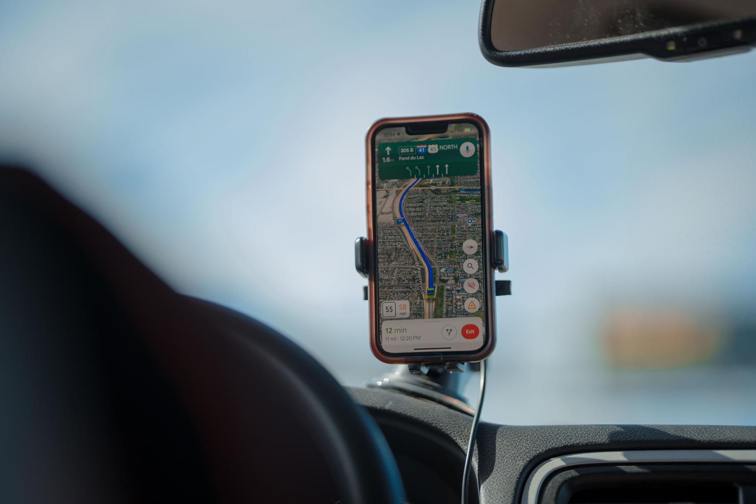 Smartphone con navegación GPS en el salpicadero de un coche, mostrando la aplicación práctica de Ask Maps en tiempo real.