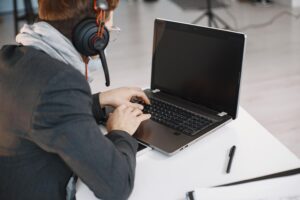 Hombre profesional con auriculares y micrófono de diadema trabajando con un ordenador portátil en un entorno de oficina.